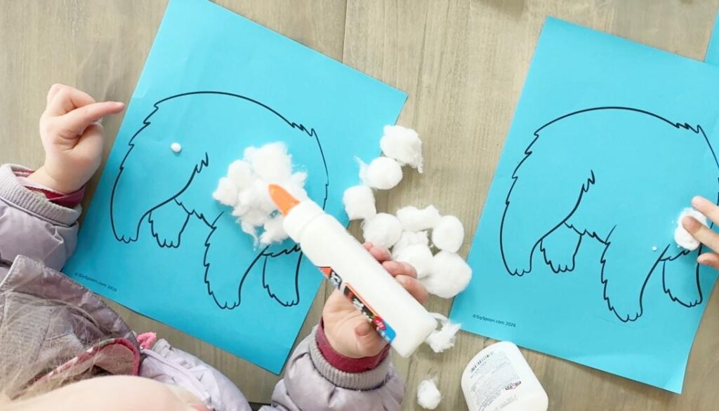 Preschool child making a polar bear craft using cotton balls and glue, creating a fluffy winter bear art project.