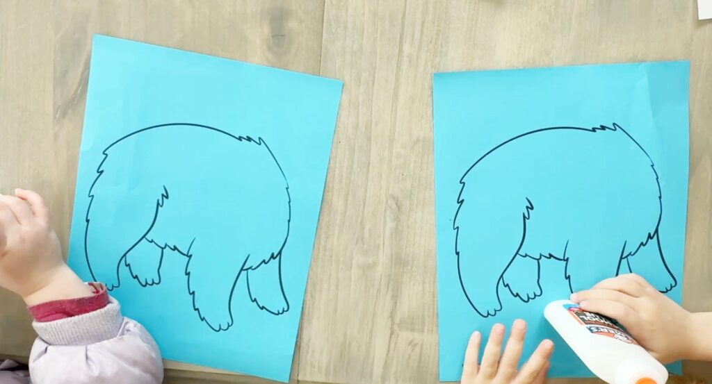 Children working on a polar bear winter craft using free printables, cotton balls, and glue in a classroom or homeschool setting.