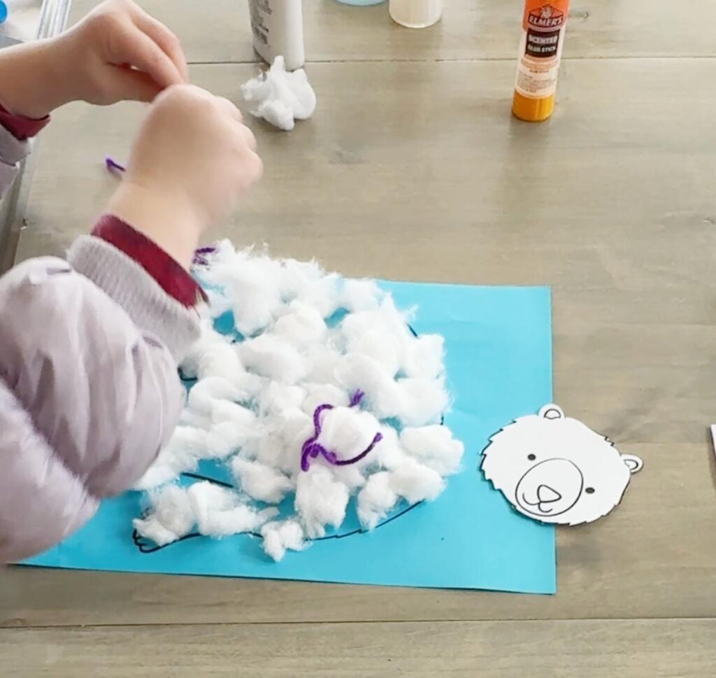 Winter polar bear craft with cotton ball body and yarn scarf, made using printable templates for preschool and early elementary kids.