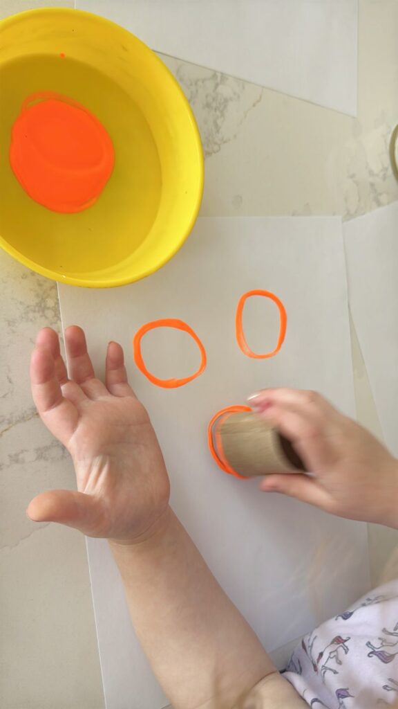 Letter O is for Orange Orchard Stamp Activity stamping with a paper tube and orange paint