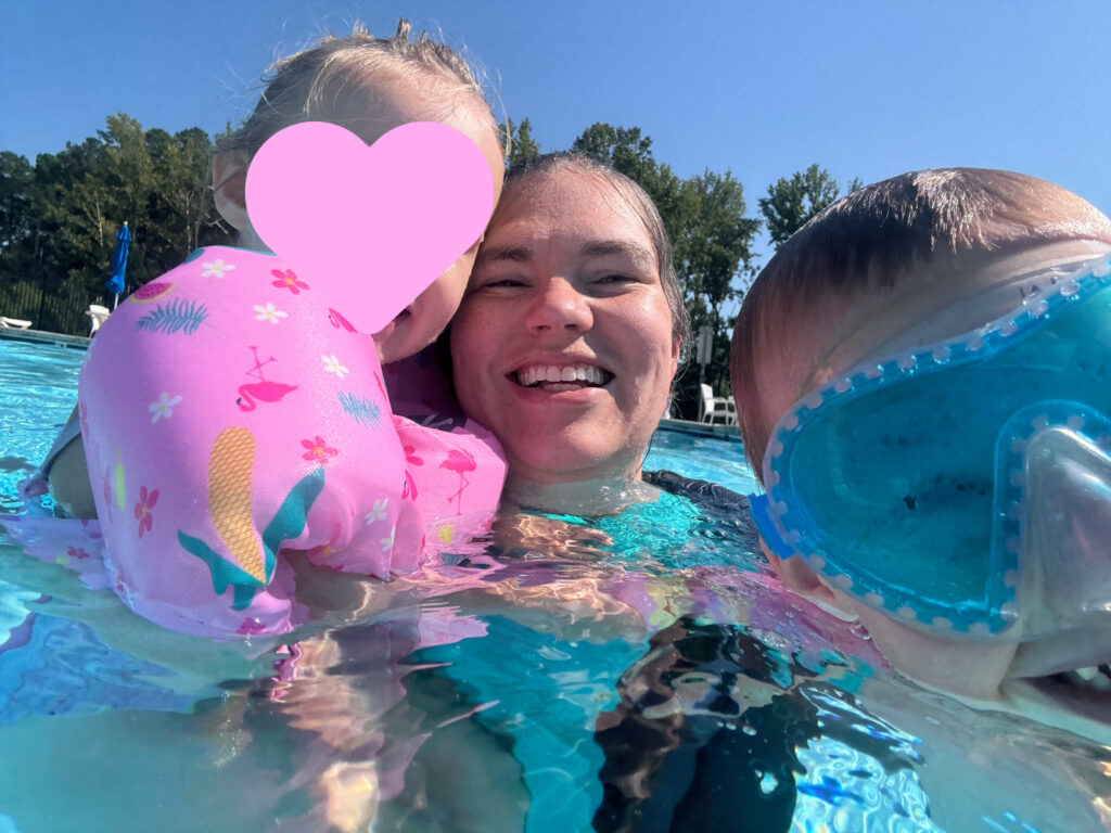 Mom wearing a Halcurt built-in bra rash guard while supervising children at a neighborhood swimming pool.