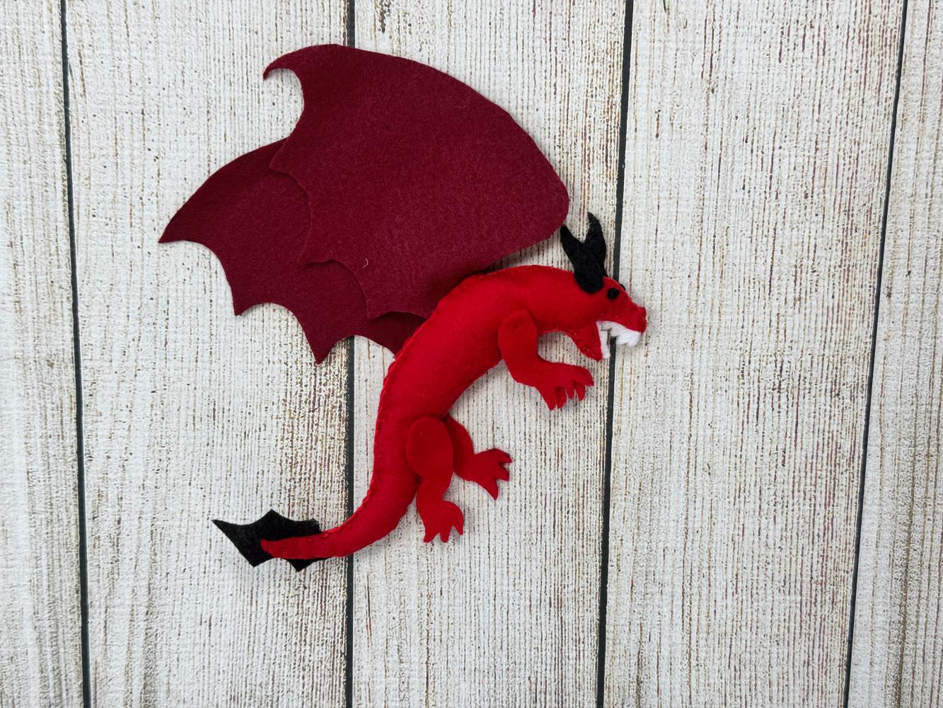 Finished blanket stitching around the edge of a red felt dragon