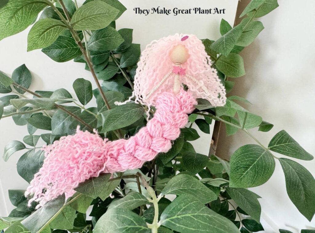 Handmade yarn mermaid displayed as bookshelf decor, plant decoration and imaginative play toy.