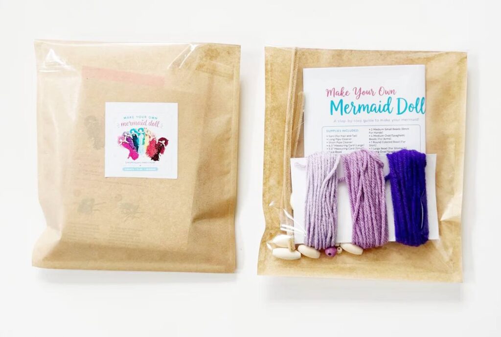 DIY mermaid craft kit for kids with yarn, wooden beads, pipe cleaners, measuring cards and printed instructions.